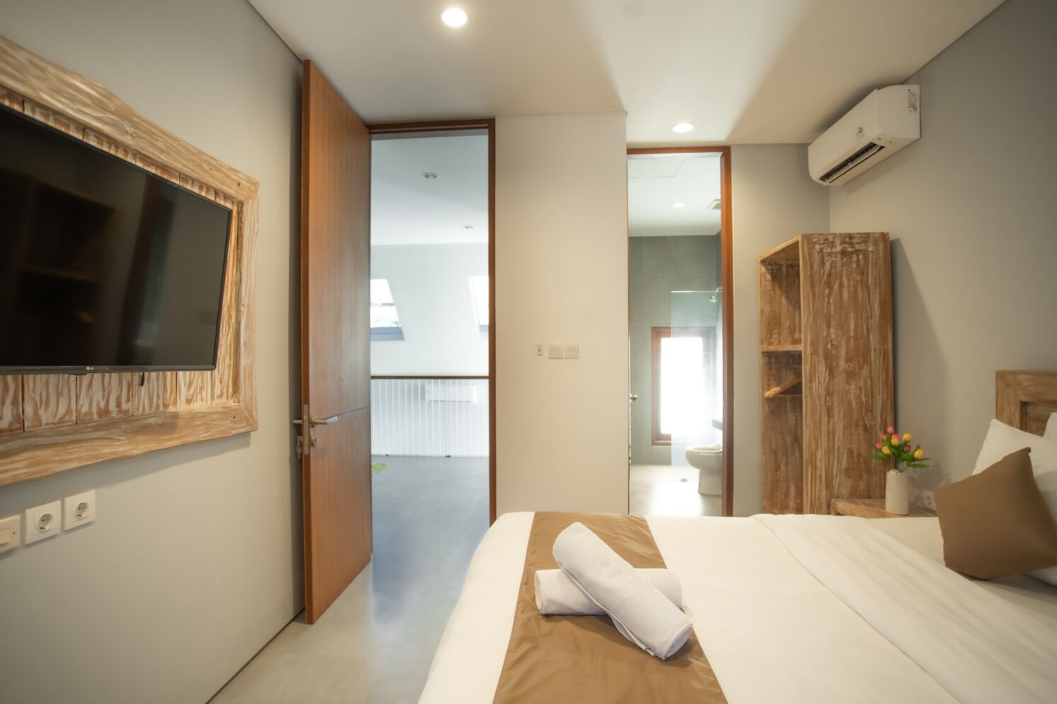 Une chambre d’hôtel moderne dotée d’un grand lit, d’un téléviseur fixé au mur et d’un appareil de climatisation.