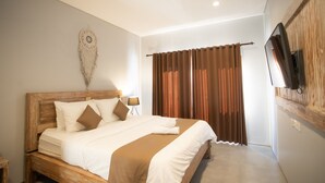 A bedroom with a wooden bed, a wall clock, a TV mounted on the wall, and brown curtains.