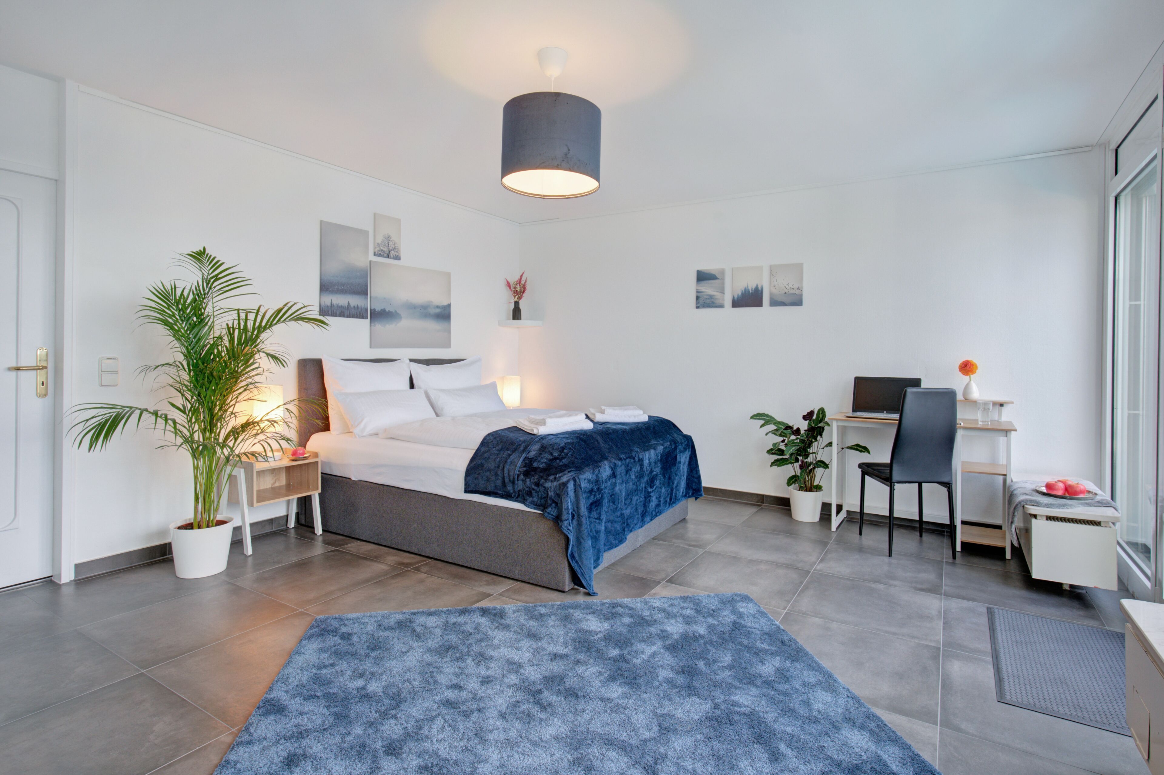 Une chambre à coucher moderne, comprenant un lit, une table de chevet, une lampe et un bureau avec une chaise.