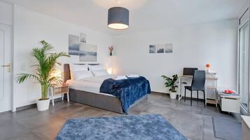 Une chambre à coucher moderne, comprenant un lit, une table de chevet, une lampe et un bureau avec une chaise.