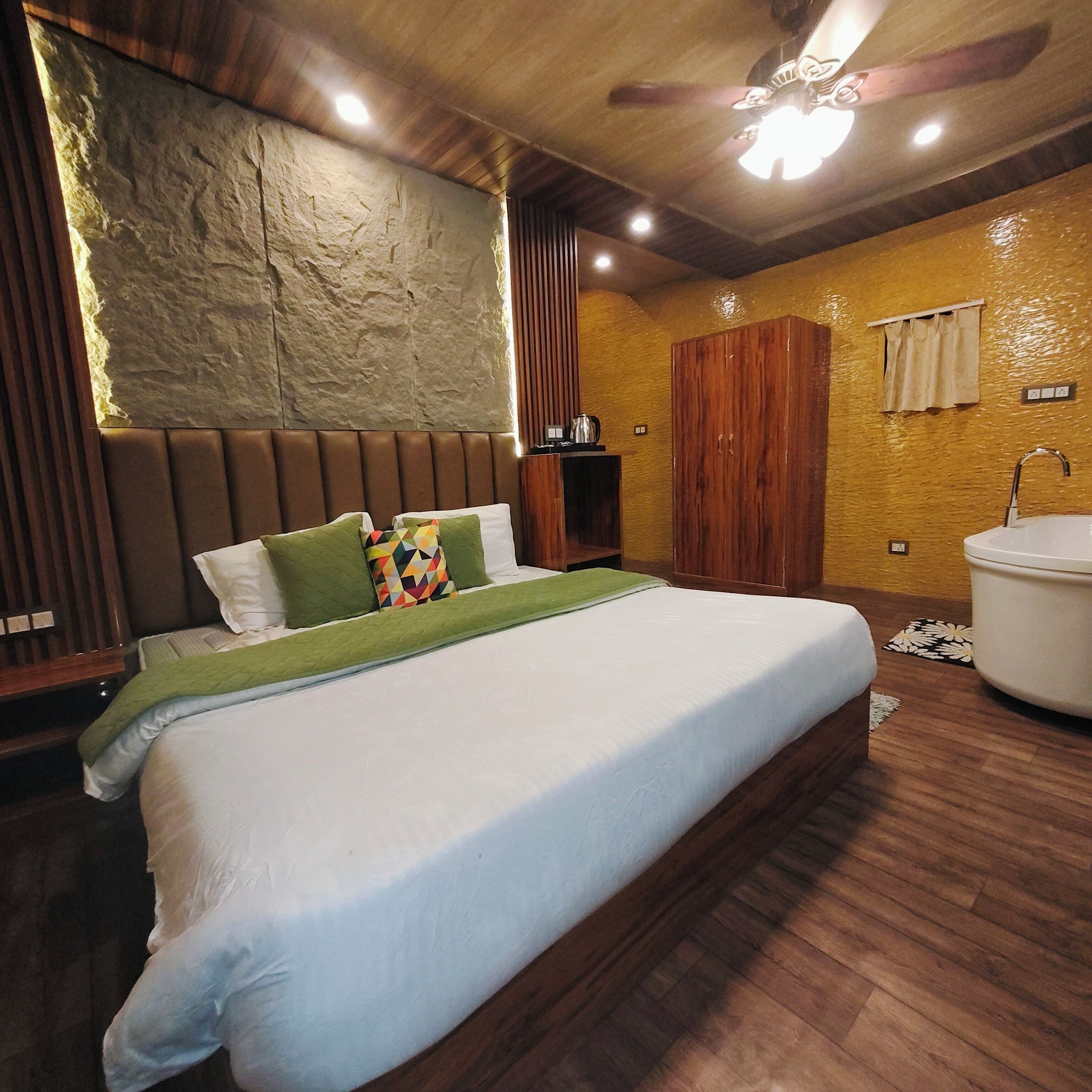 Een slaapkamer met een groot bed, een houten garderobe, een badkamer met een badkuip en een structuurwand.
