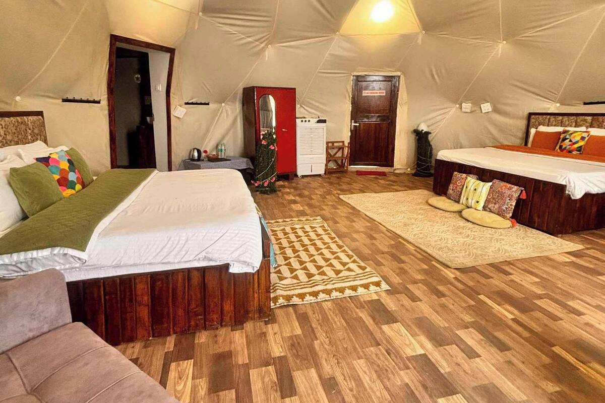 Eine Zelthütte mit zwei Betten, einer Couch und einem Kleiderschrank.