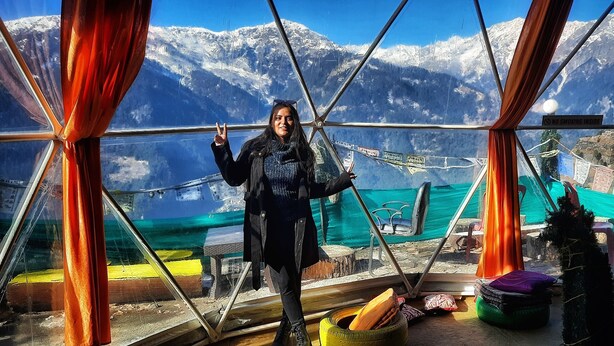 A person inside a glass structure with a view of snow-capped mountains. - Nirvana Hamta Retreat (Manali)