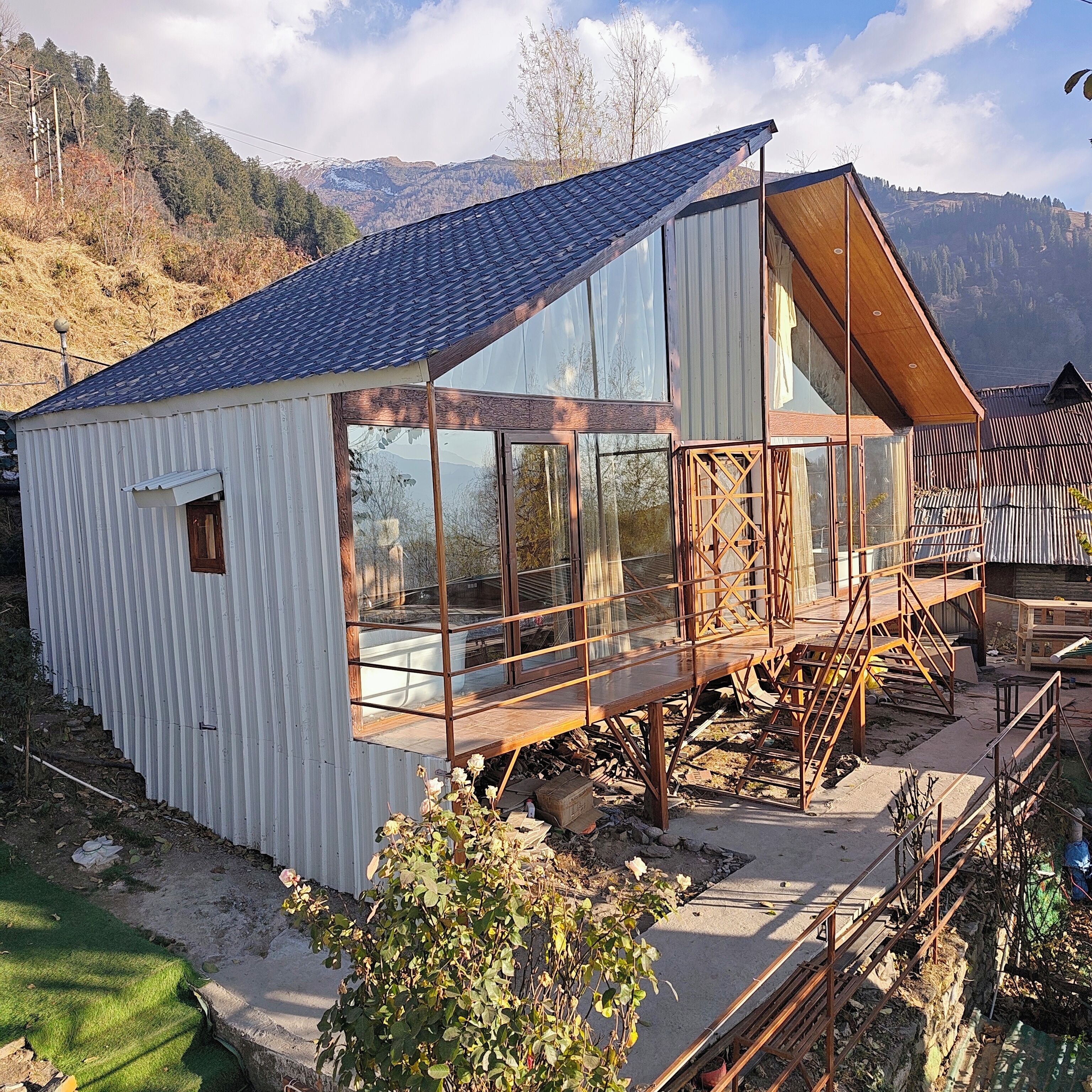 A modern building with large windows and a sloped roof, surrounded by a natural landscape.