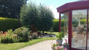 A garden with a pathway leading to a conservatory with glass doors. - Peaceful Forest Stay in Pédernec (Pedernec)