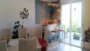 A dining area with a table, chairs, and a bar area with shelves and a hanging light fixture. - Peaceful Forest Stay in Pédernec (Pedernec)