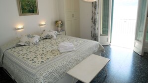 Une chambre à coucher avec un lit, des lampes de chevet, un tableau, une armoire et un balcon.