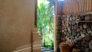 A rustic interior with a stone wall, a wooden fence, and a small garden visible through an opening. - duegoal farmhouse (Penebel)