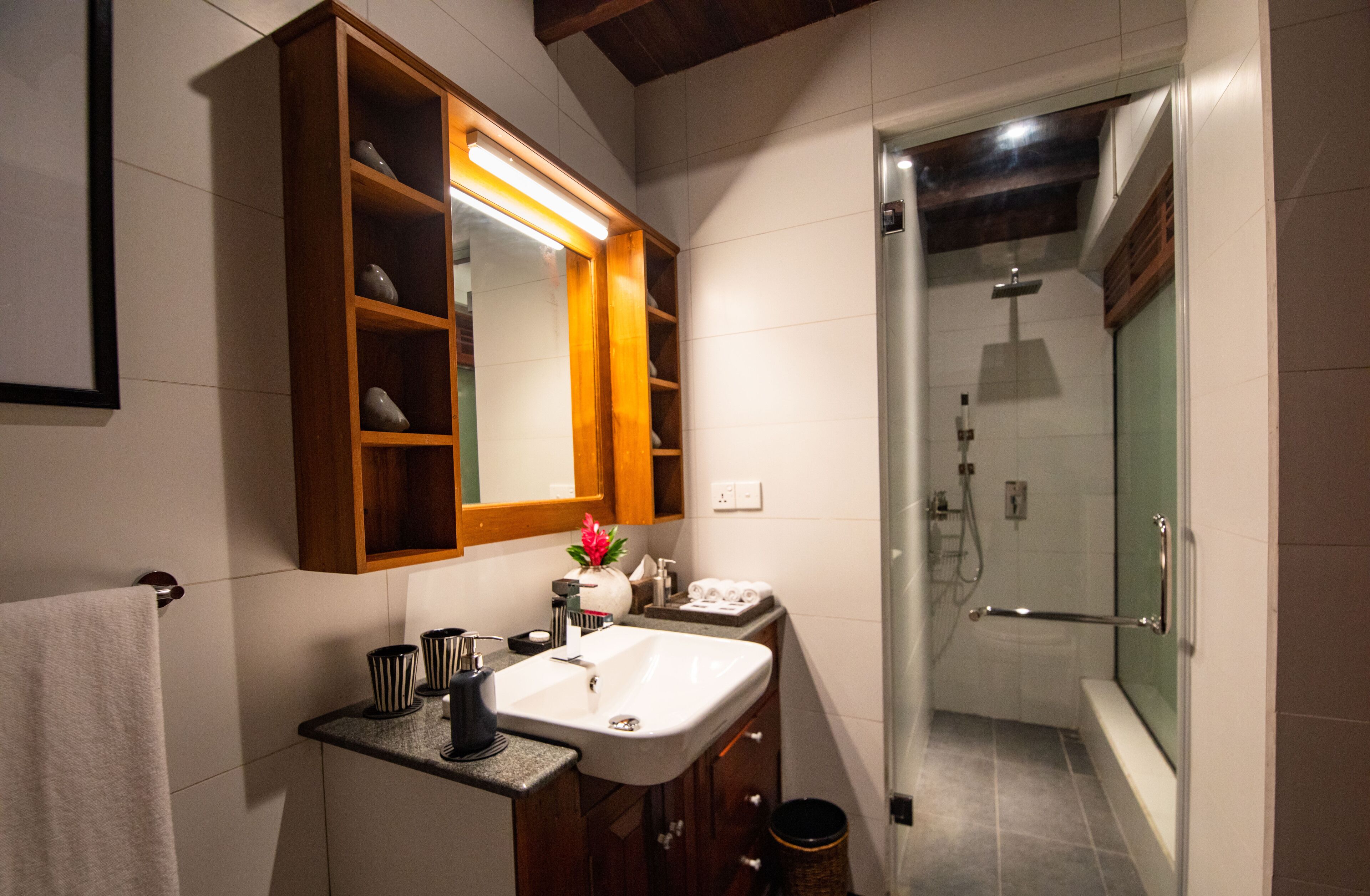 Une salle de bain moderne avec un grand miroir, un lavabo et une douche.