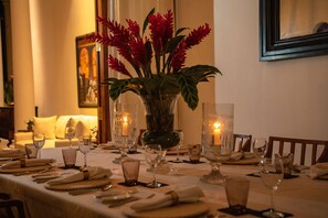A dining table set for a meal with candles, glasses, and a vase of flowers. - Nyne Hotels Landesi - Galle Fort (Galle)