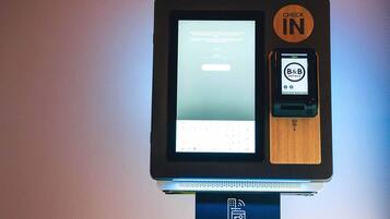 Quiosco de auto-check-in con pantalla digital e interfaz para dispositivos móviles de B&B Hotels.