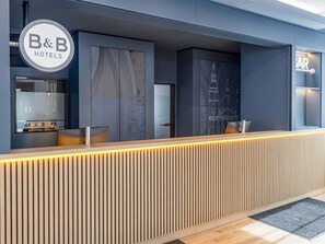 A reception desk with a modern design, featuring a logo for B&B Hotels. - B&B Hotel Fulda-Hbf (Fulda)