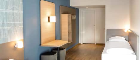 Una habitación de hotel con dos camas, un escritorio de madera, un espejo y un armario.