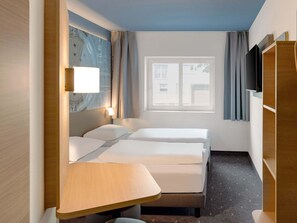 A hotel room with two beds, a desk, a TV, and a window with curtains. - B&B Hotel Fulda-Hbf (Fulda)