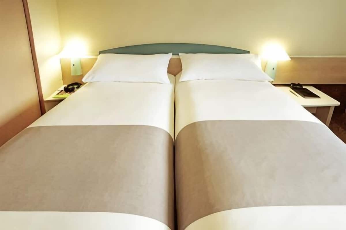 A double bed with two bedside tables, each with a lamp and a phone.