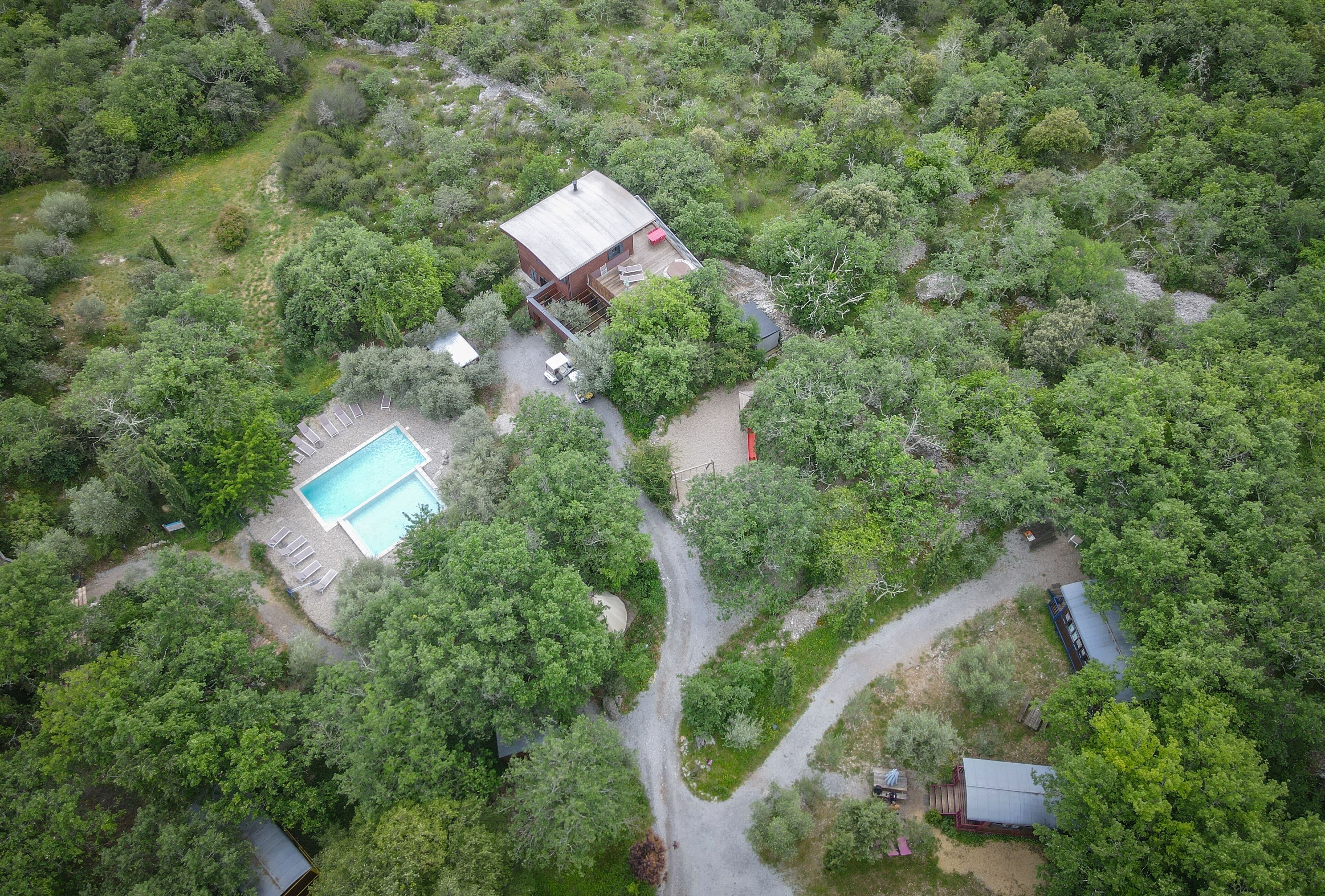 An aerial view of a property with a swimming pool, a small building, and a boat dock.