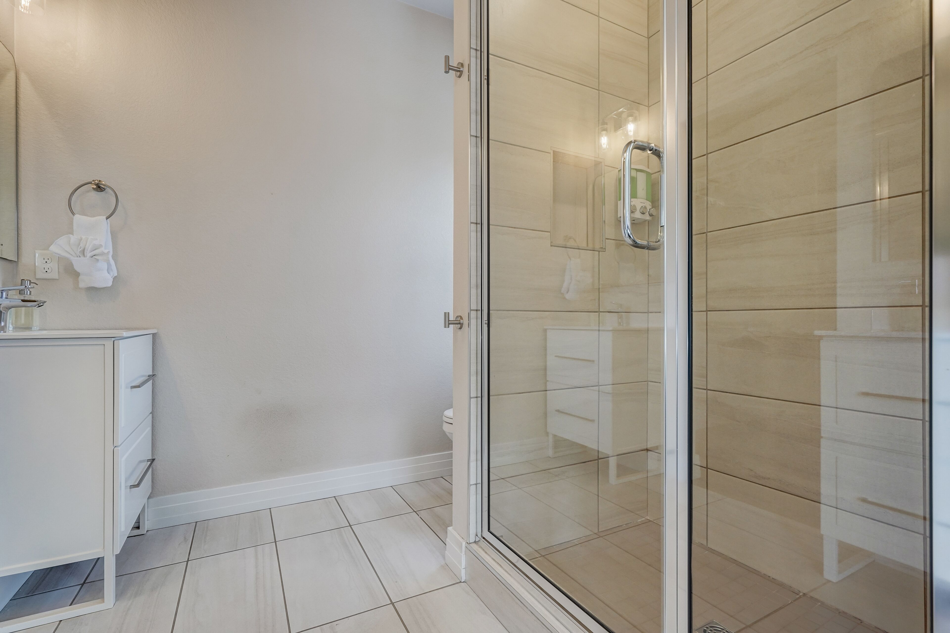 A modern bathroom with a glass shower enclosure, a white vanity, and a toilet.