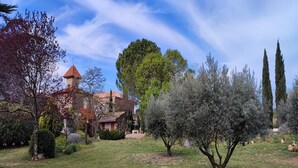 A traditional building with a tower, surrounded by a well-maintained garden with various trees and shrubs. - Spacious holiday home with private pool and park (Puisserguier)