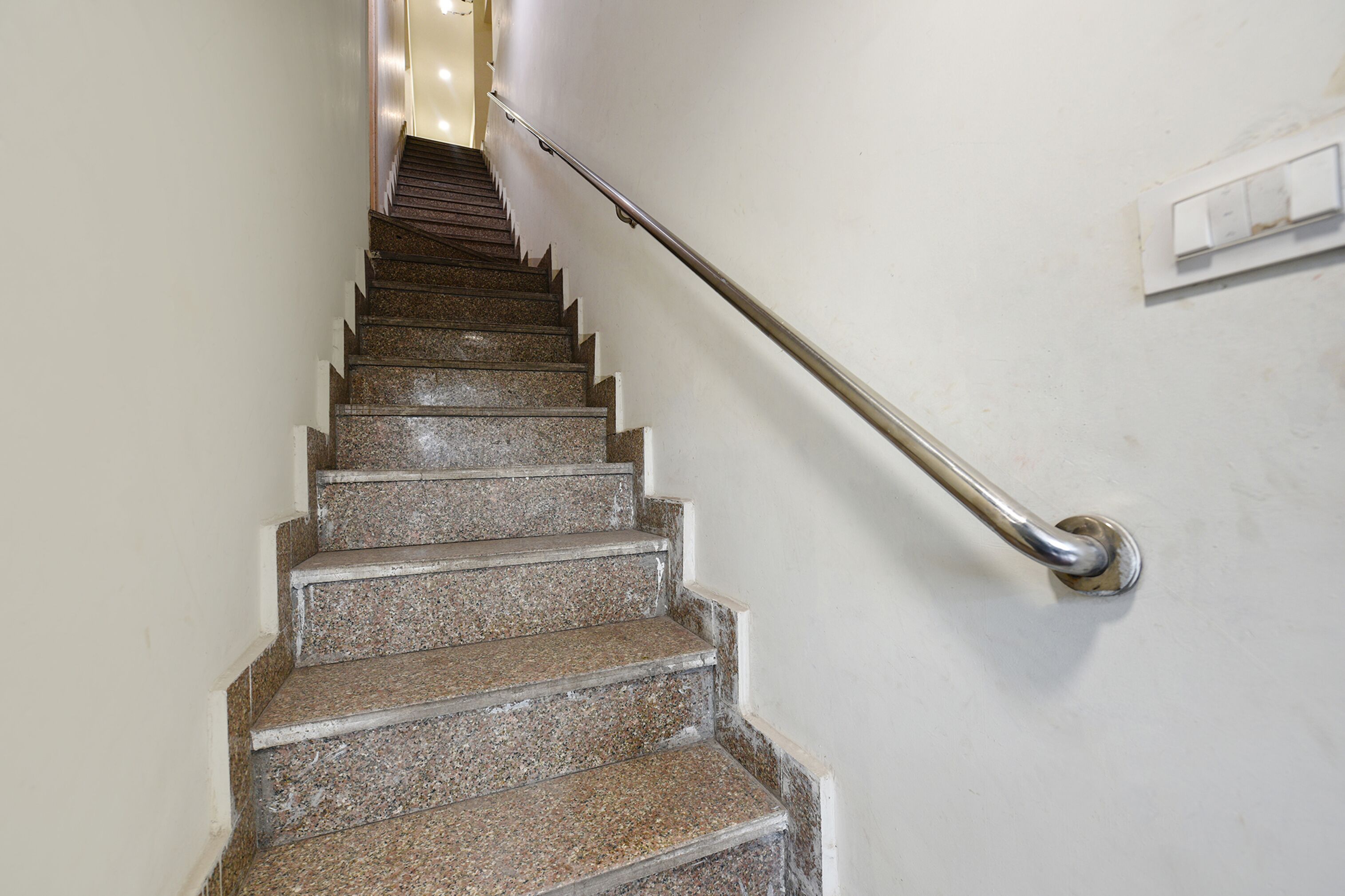 A staircase with granite steps and a metal handrail.