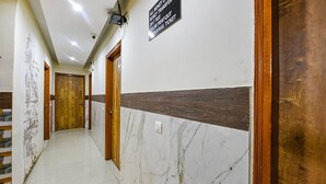 A hallway with marble flooring, wooden doors, and a sign indicating a money transfer service. - FabHotel Shanti Stay (New Delhi)