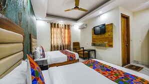 A hotel room with two beds, a ceiling fan, a TV mounted on the wall, and a door. - FabHotel Shanti Stay (New Delhi)