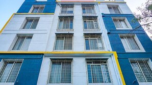 Ein mehrstöckiges Gebäude mit blau-weißer Fassade, ausgestattet mit großen Fenstern und Metallgitter.