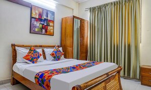A bed with a colorful quilt, a wooden headboard, and a wardrobe. - Fabhotel Grandeur (Pune)
