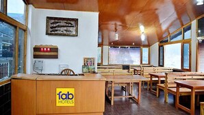A spacious room with wooden furniture, a reception desk, and large windows offering views. - Fabhotel Whistling Winds (Manali)