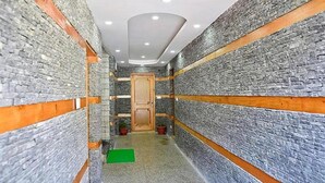 A narrow hallway with stone walls and wooden accents, leading to a door. - Fabhotel Whistling Winds (Manali)