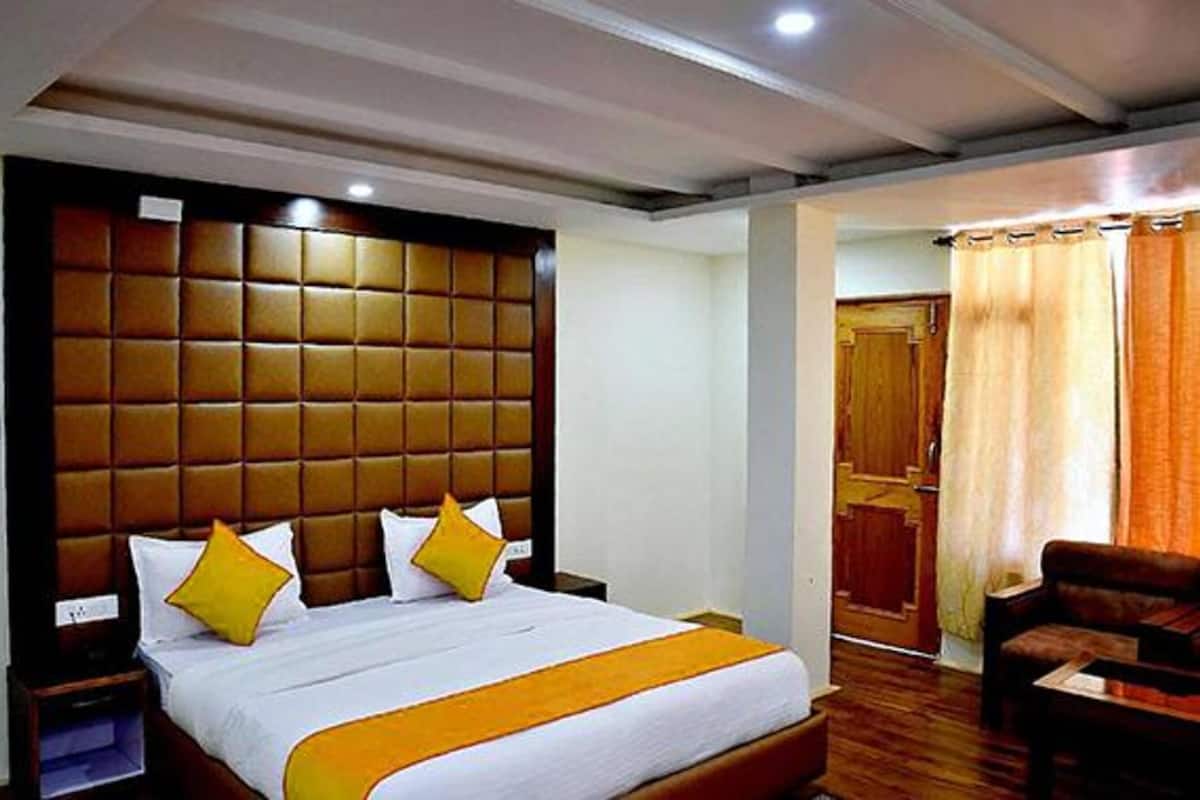 A hotel room with a large bed, a wooden headboard, and a small seating area with a chair and table.
