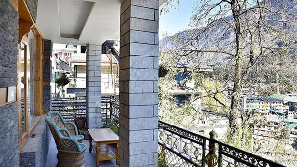 A balcony with wicker furniture and a stone pillar. - Fabhotel Whistling Winds (Manali)