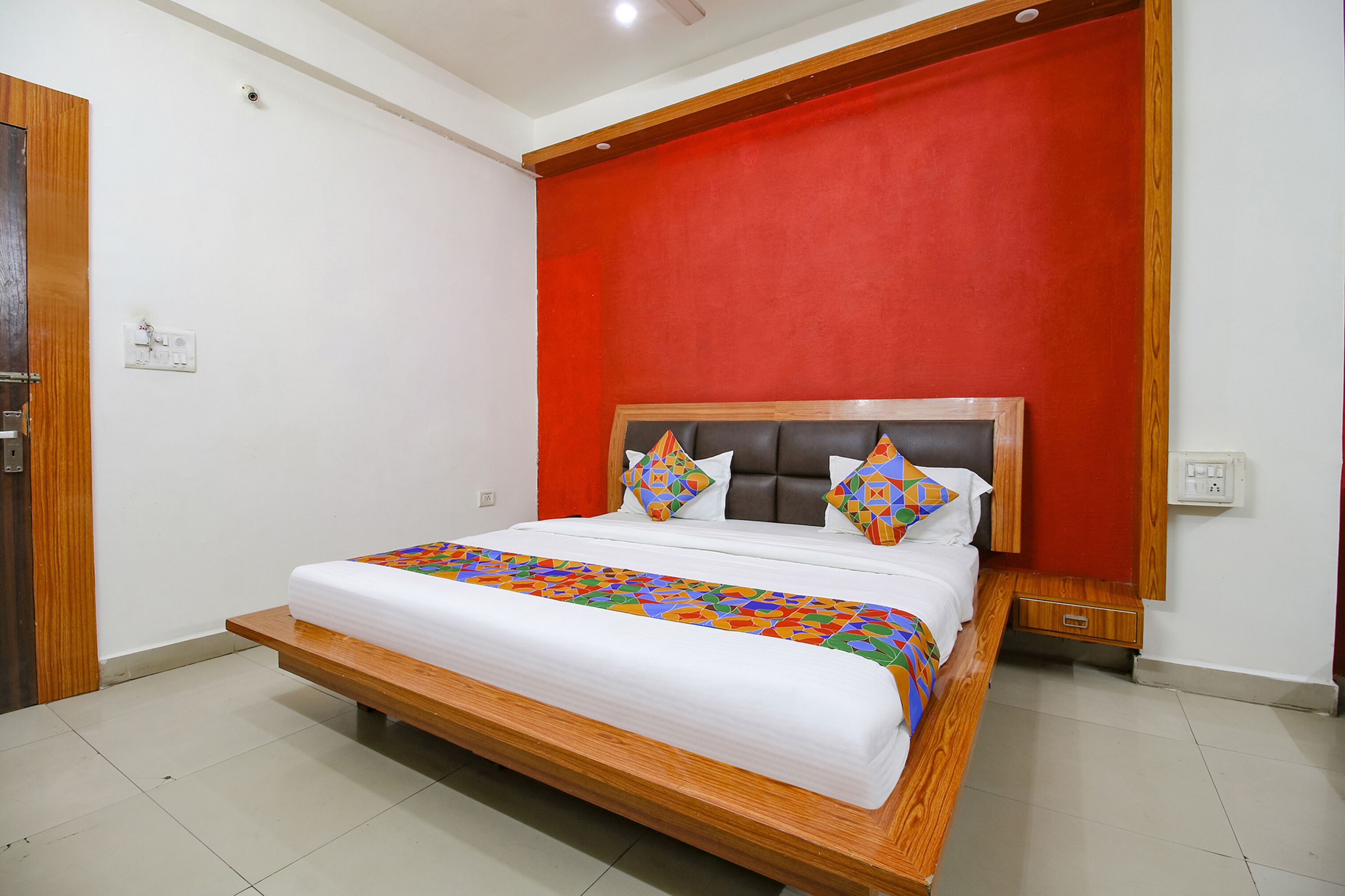 Un dormitorio con una cama grande, una pared de acento roja y un cabecero de madera.