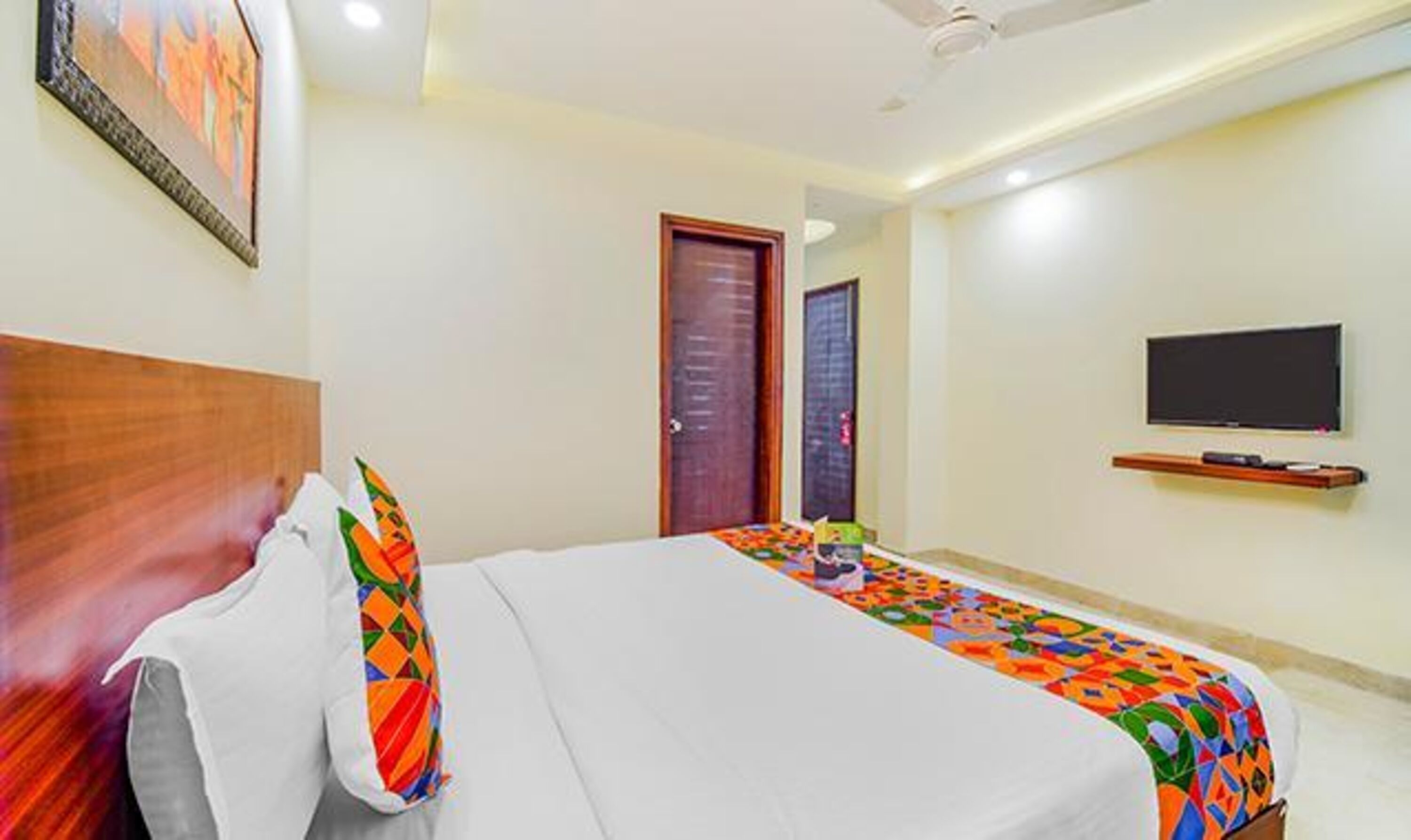 A hotel room with a bed, a TV, and a door.