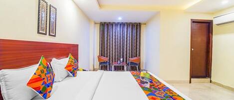 A hotel room with a bed, two chairs, a small table, and a door.