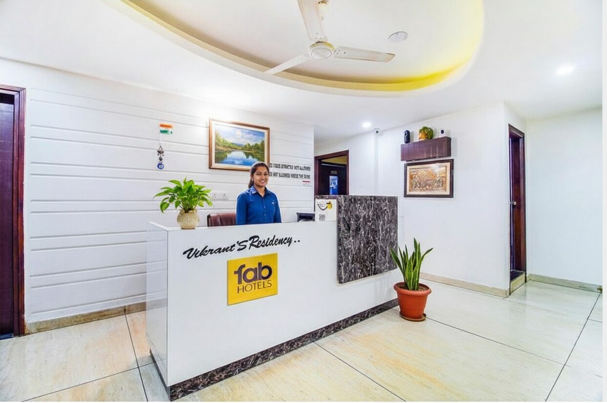 A reception desk with a sign reading "Vibrant's Residency - Fab Hotels".