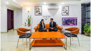 A modern waiting area with a sofa and chairs, a coffee table, and decorative elements like plants and artwork.