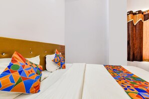 A hotel room with a neatly made bed, a headboard, and a window with curtains. - Fabexpress Raj Palace (Udaipur)