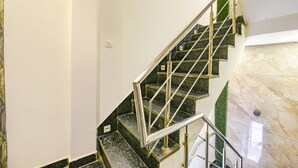 Una escalera con barandilla de metal, escalones de mármol y una pared de acento verde.