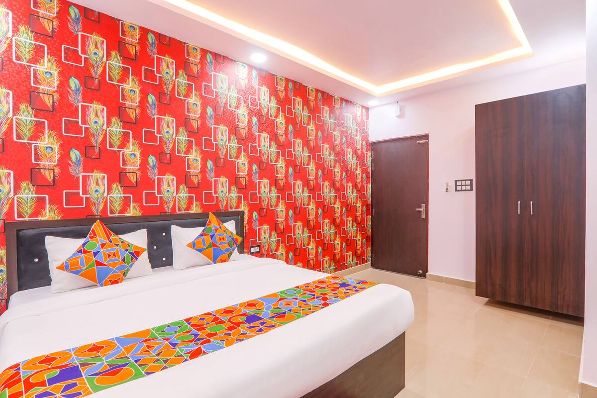 A hotel room with a bed, a wardrobe, and a red patterned wall.