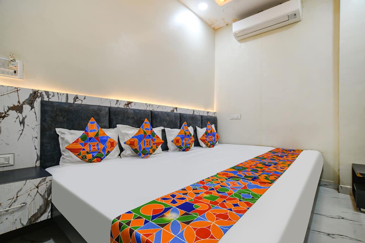 A hotel room with a large bed, a marble nightstand, a modern headboard, and a patterned bed runner.
