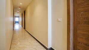 A corridor with marble flooring, beige walls, and a wooden door. - Fabhotel Stargaze (Kanpur)