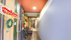 A hallway with a 'Merry Christmas' sign, Christmas wreaths, and a seating area with a brown sofa and chairs. - Fabexpress Abis Residency (Kolkata)