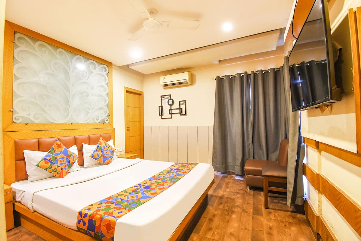 Une chambre d’hôtel avec un grand lit, un téléviseur fixé au mur et une tête de lit en bois.