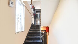 A staircase with a handrail, a window on the left, and a door at the top. - Fabexpress Abis Residency (Kolkata)