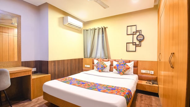 A hotel room with a bed, desk, and wardrobe. - Fabexpress Abis Residency (Kolkata)