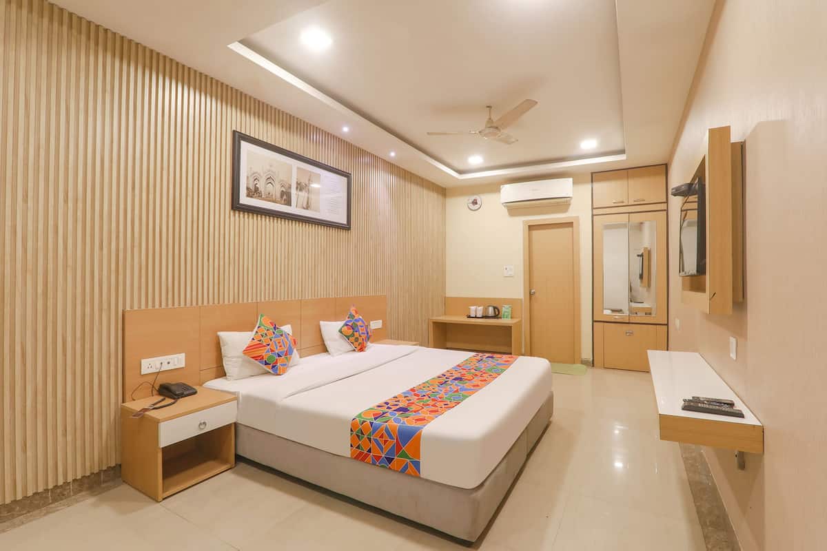 Una habitación de hotel con cama, mesita de noche y un pequeño escritorio con silla.