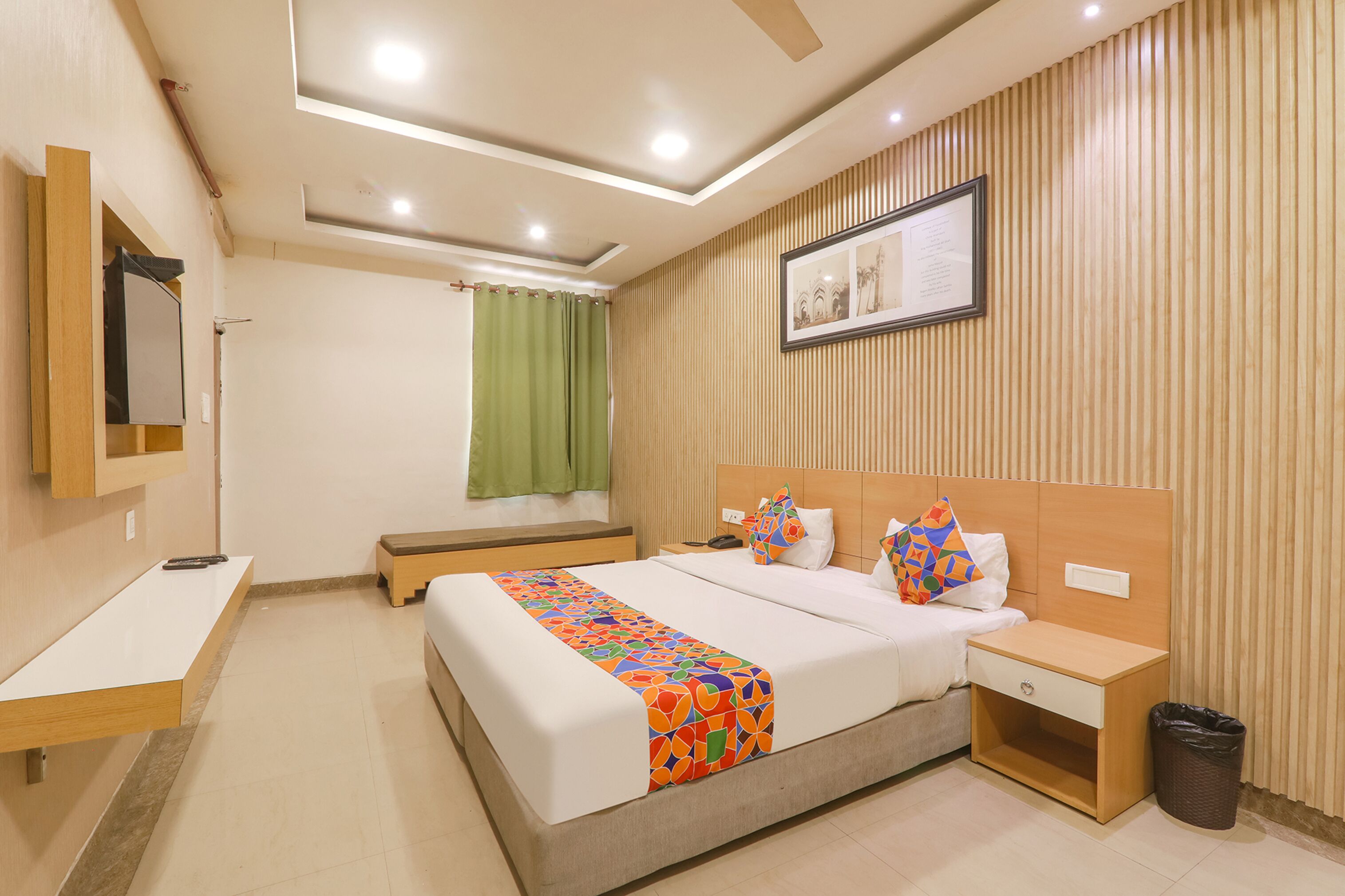 A hotel room with a bed, bedside table, nightstand, and a trash bin.