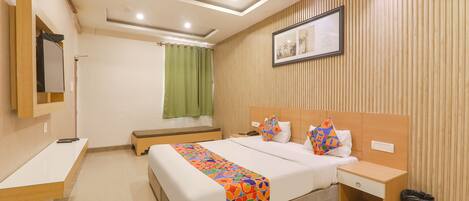 A hotel room with a bed, bedside table, nightstand, and a trash bin.