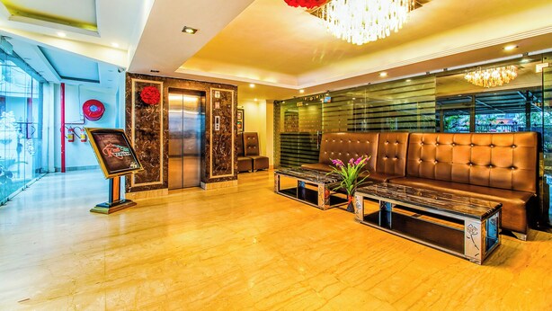 Una hall moderna con pavimento in legno, un divano in pelle marrone, un lampadario rosso e un ascensore decorato con un fiore rosso.