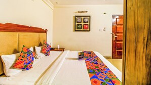 Una camera d'albergo con un letto matrimoniale, una testiera in legno, una ventola a soffitto e un quadro appeso alla parete.